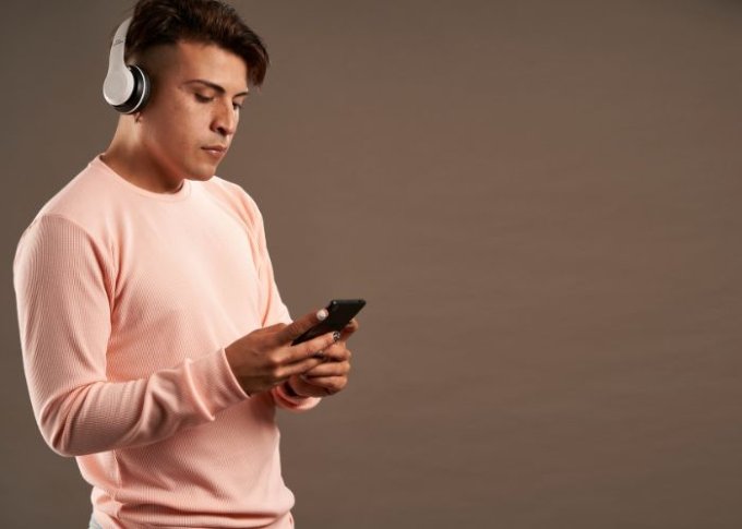 Młody mężczyzna używa słuchawek bezprzewodowych ze smartfonem